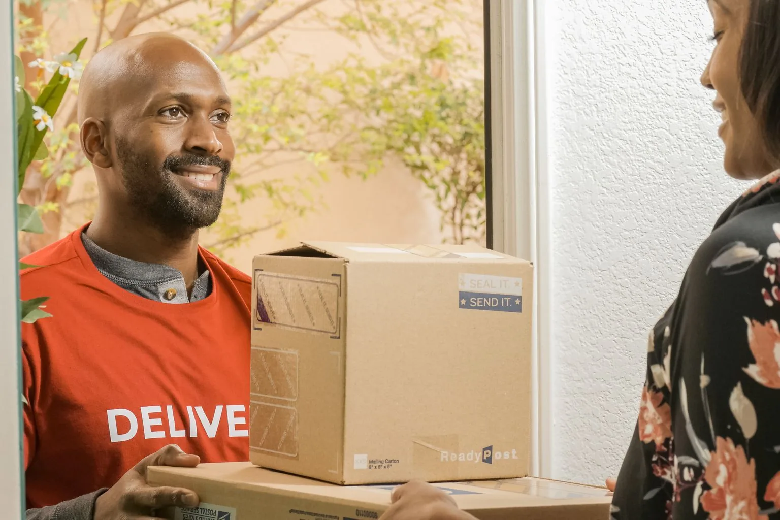 A delivery worker handing parcels to a recipient at a doorway.