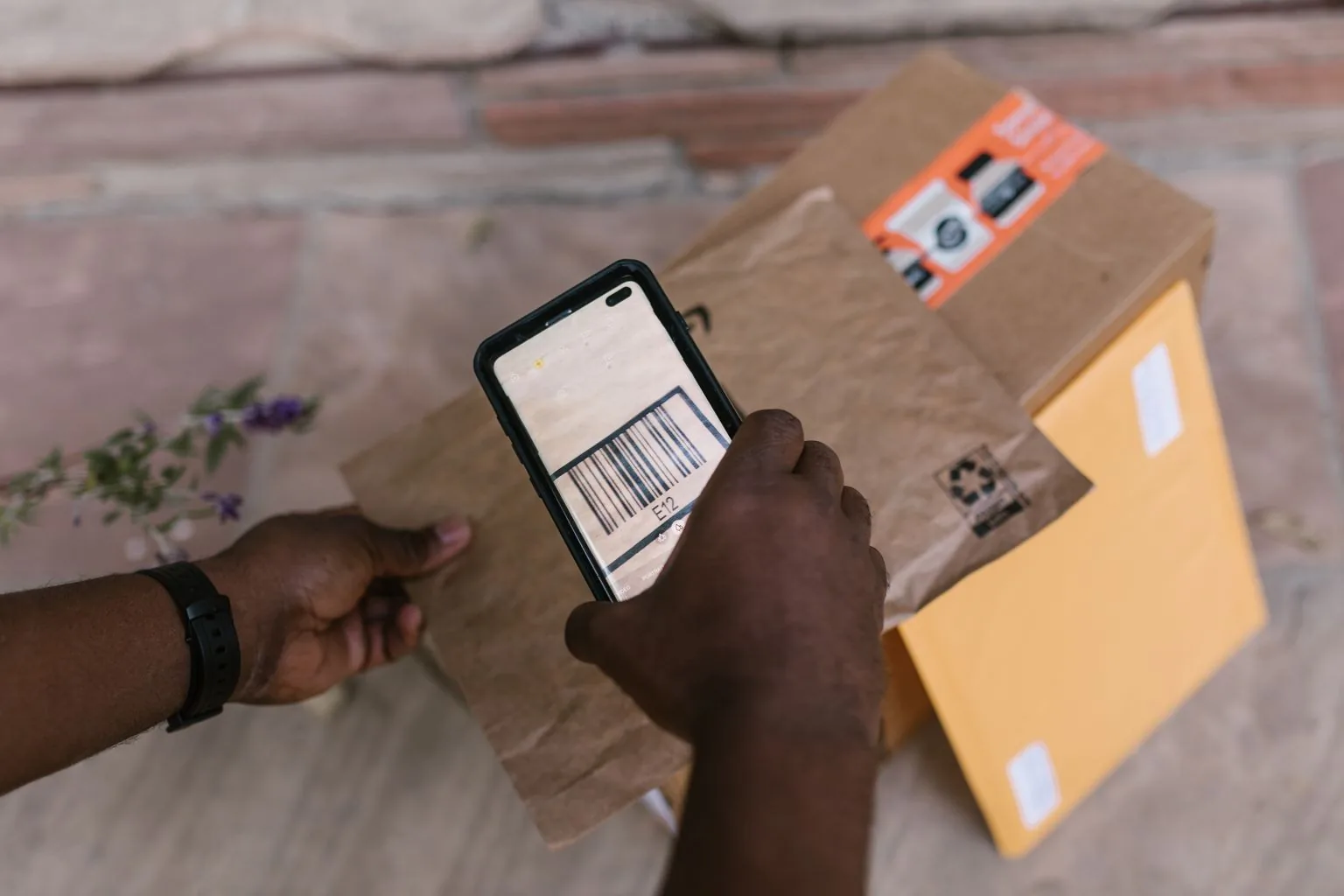 Hands scanning a parcel barcode with a smartphone.